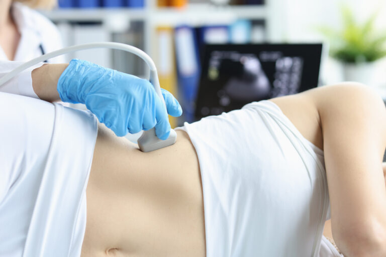 Doctor making ultrasound of liver to patient in clinic closeup. Diagnosis and treatment of non-alcoholic fatty liver disease.